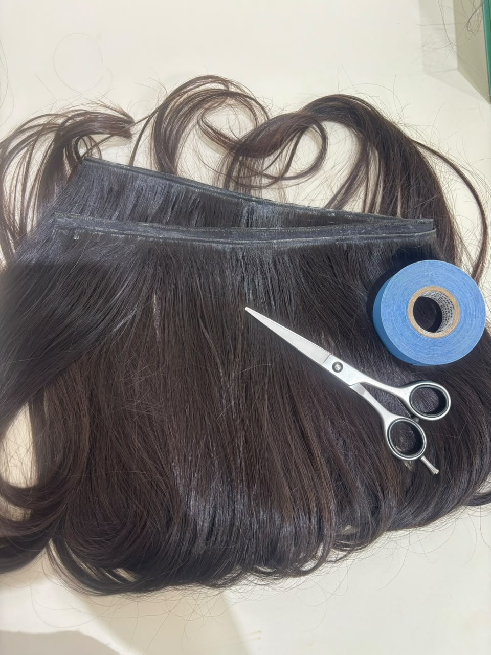 Mãos segurando mecha de mega hair com fita adesiva